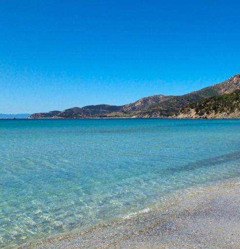 Persona su scogliera ammira spiaggia e mare cristallino, panorama mozzafiato.